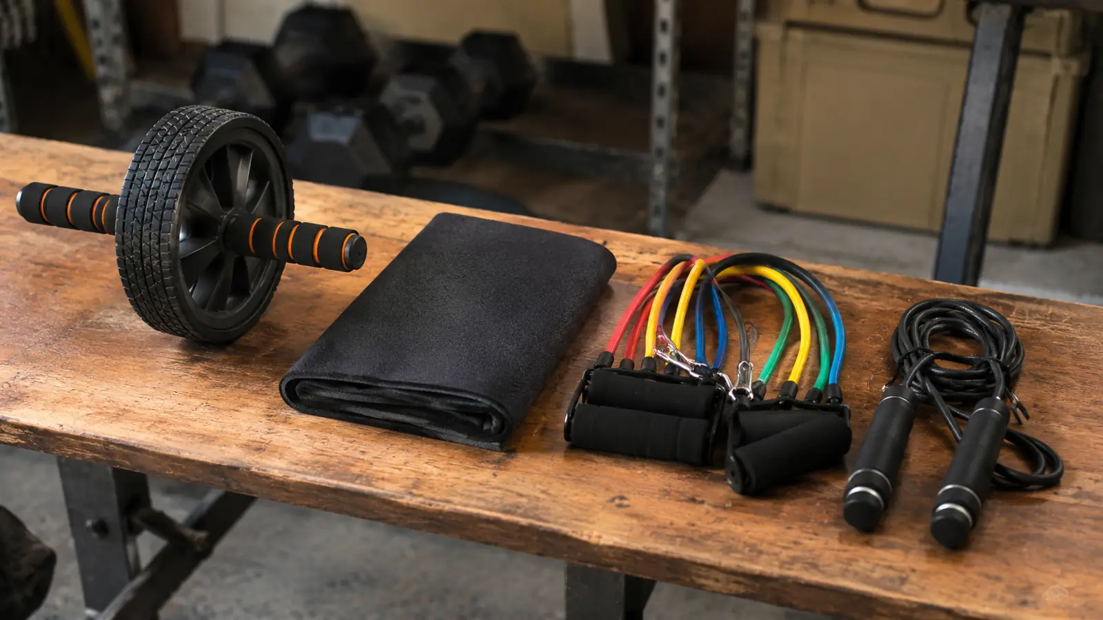 An ab roller wheel with the extra mats and band handles from the kit laid out on a garage bench.